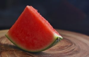 Foto de uma melancia sem caroço sobre uma mesa de madeira em um fundo escuro